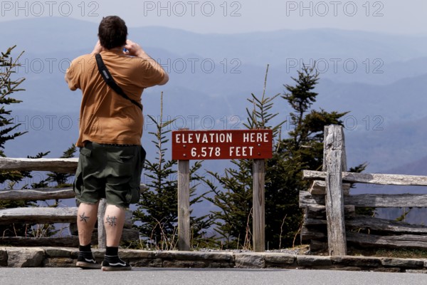 A tourist photographs the landscape at the viewpoint of Mount Mitchell State Park, Mount Mitchell State Park, North Carolina, USA