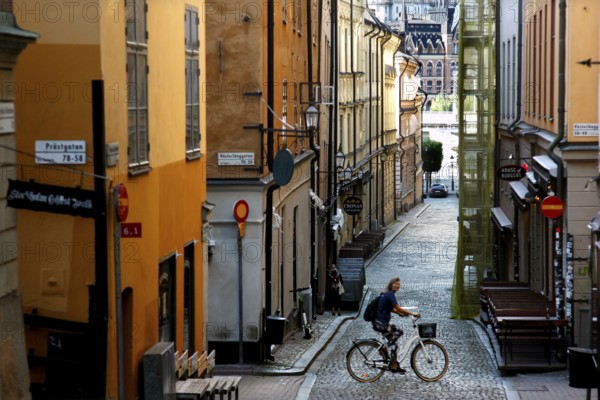 A cyclist in a picturesque old town alleyway in Stockholm, surrounded by charming buildings, Stockholm, Gamla Stan, Sweden