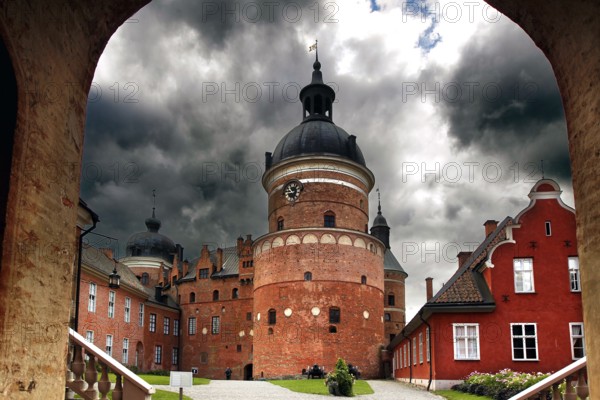 Gripsholm Castle in Mariefred through an archway with a heavily cloudy sky, Mariefred, Södermanland, Sweden