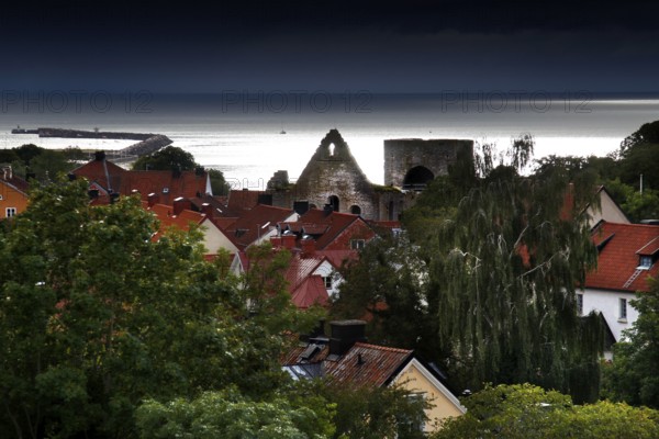 View of Visby's old town with red roofs and church ruins, surrounded by lush greenery and sea views, Visby, Gotland, Sweden