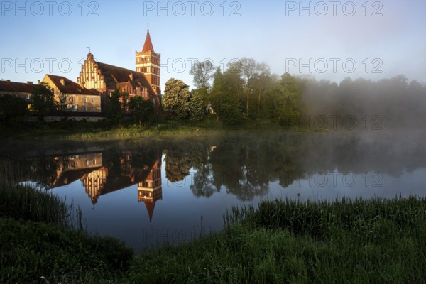 St. George's Church is picturesquely reflected in the quiet mill pond, Pravdinsk, Kaliningrad, Russia