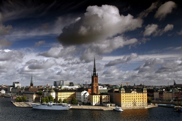 View of Riddarholmen in Stockholm with distinctive church tower and dramatic sky seen from Södermalm, Stockholm, Sweden