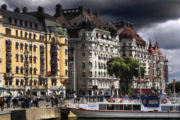Historic buildings along Strandvägen with boats in water and dramatic sky, Stockholm, Östermalm, Sweden
