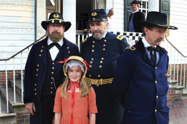Soldiers in historic uniforms with a girl on the street in Colonial Williamsburg, Williamsburg, Virginia, USA