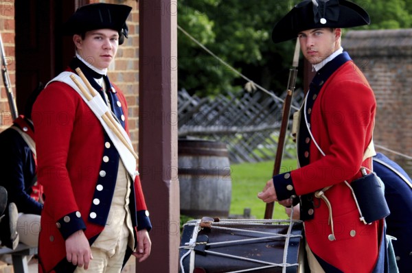 Two soldiers in red historic uniforms stand in front of a building and look alert, Williamsburg, Virginia, USA
