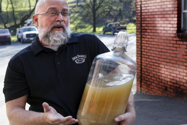 An employee from Jack Daniel's Distillery shows a large glass container, Lynchburg, Tennessee, USA