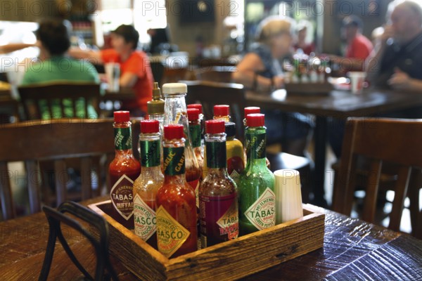 Different Tabasco bottles in the foreground of a restaurant, Avery Island, Louisiana, USA