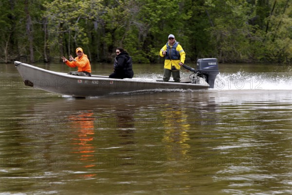 A fast motorboat with three people passes through the swampy area of the Atchafalaya Basin, zero