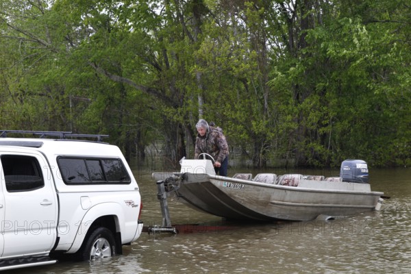 A pickup truck pulls a boat into the water at the Atchafalaya Basin, surrounded by dense forest, zero
