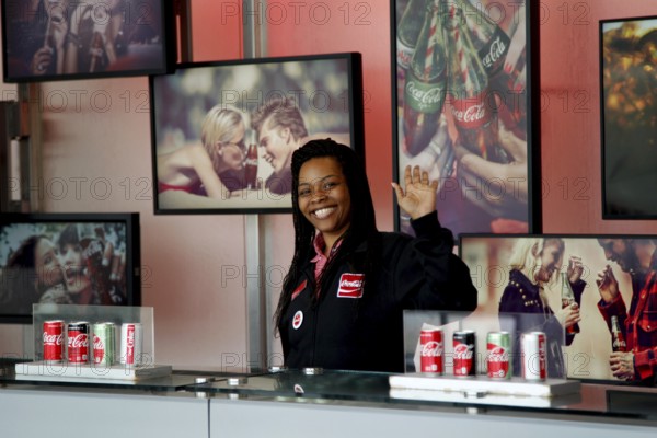 An employee of the Coca-Cola Museum in Atlanta, surrounded by cola cans and photographs, Atlanta, USA