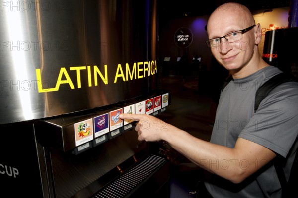 A man in the tasting room of the Coca-Cola Museum in Atlanta enthusiastically points to drinks from Latin America, Atlanta, Georgia, USA