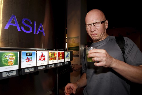 A man in the tasting room of the Coca-Cola Museum in Atlanta tastes Asian drinks with curious facial expressions, Atlanta, Georgia, USA