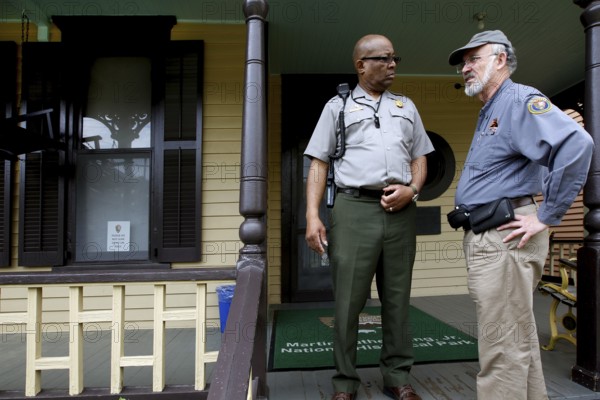Two men in uniform talk on the front porch of Martin Luther King Jr. ' s Birthplace, Atlanta, Georgia, USA