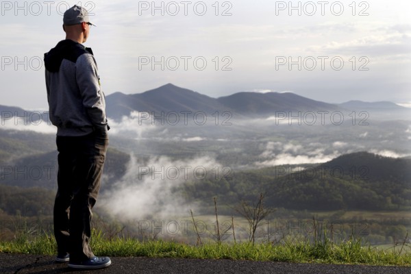 Man standing at Blue Ridge Parkway looking over misty mountain landscape, Blue Ridge Parkway, Virginia, USA