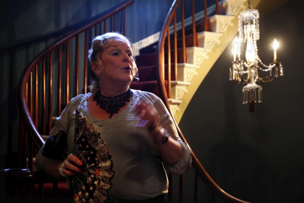 Elegant woman with fan posing in illuminated room at Houmas House, Houmas House, Louisiana, USA