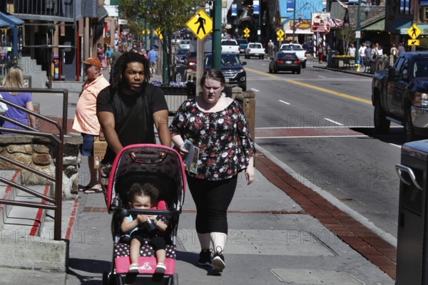 Family with stroller walking down the sunny main street of Gatlinburg, Gatlinburg, Tennessee, USA