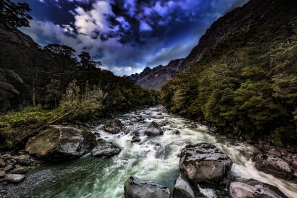 Torrential river through a wooded gorge under a dramatic sky