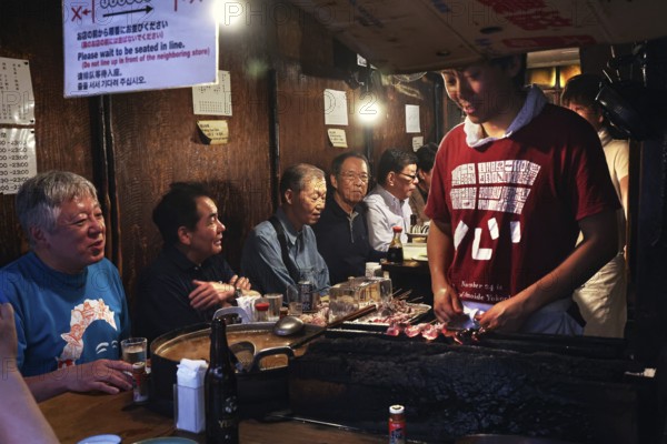Visitors enjoy yakitori in a cozy bar in Shinjuku, Tokyo, Japan