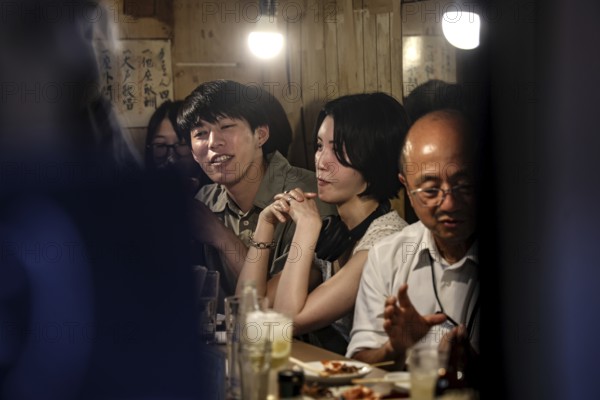 Group of people enjoying yakitori in a Shinjuku bar, Tokyo, Japan