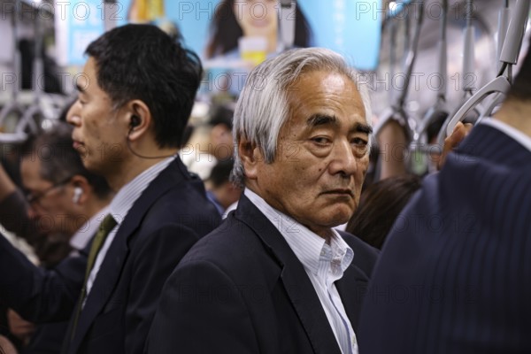 Commuters ride on a busy subway in Tokyo, Tokyo, Japan