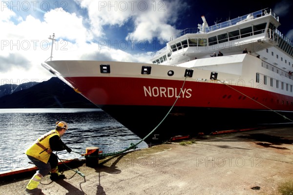 Hurtigruten ship moored at quay, man mooring lines, Øksfjord, Norway