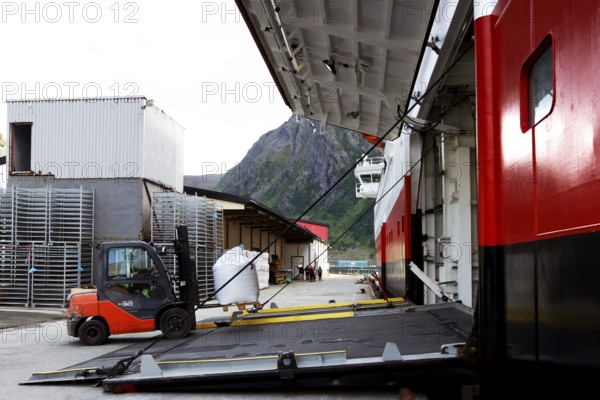 Hurtigruten ship in harbor with open cargo hatch with view of nearby mountainside, Øksfjord, Finnmark, Norway