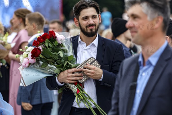 A man with a bouquet of flowers is enjoying the graduation ceremony in a festive atmosphere, Vilnius, Vilnius County, Lithuania