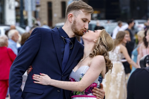 A young couple kisses during a high school graduation ceremony in a busy square, Vilnius, Vilnius County, Lithuania