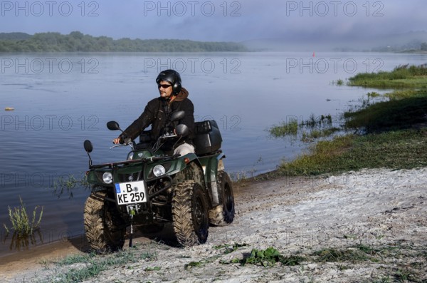 Person riding an ATV on the banks of the Nemunas River near Vilkija, Vilkija, Lithuania