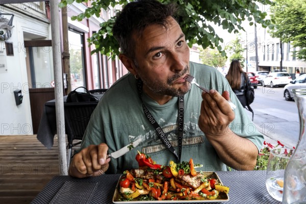 Man eats at an outdoor table at Chacapuri restaurant in Vilnius, Vilnius, Vilnius County, Lithuania