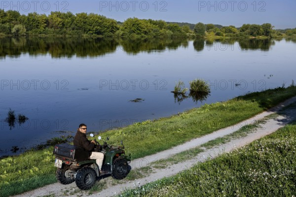 Person rides ATV on a path along the Nemunas River near Vilkija, Vilkija, Lithuania