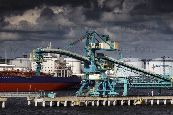 View of a harbor with cranes and a ship, dramatic clouds in the background, Ventspils, Latvia
