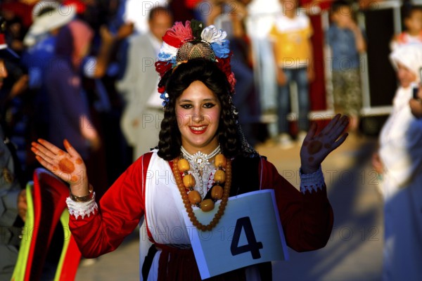 Smiling woman in traditional dress taking part in the Fête des Roses, El Kelâa m'Gouna, Marrakesh-Safi, Morocco