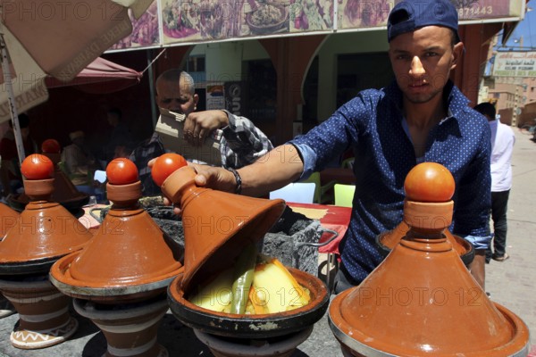 Traditional Moroccan cuisine with several brown tagine pots in a restaurant, El Kelâa m'Gouna, Morocco