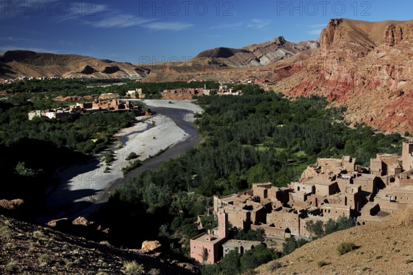Contrasting landscape with clay buildings, river and mountains in the valley, El Kelâa m'Gouna, Valley of Roses, Morocco