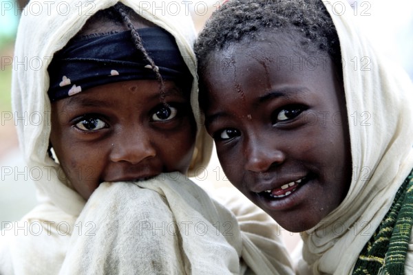 Two children wearing traditional clothes smile during a church service
