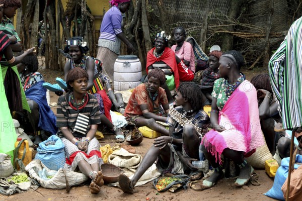 People in colorful clothes sit at a market and exchange goods