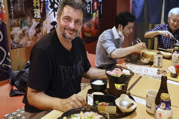 Person enjoying food at a sumo-themed restaurant, Tokyo, null, Japan