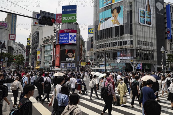 People cross the well-known Shibuya intersection surrounded by billboards, Tokyo, Japan