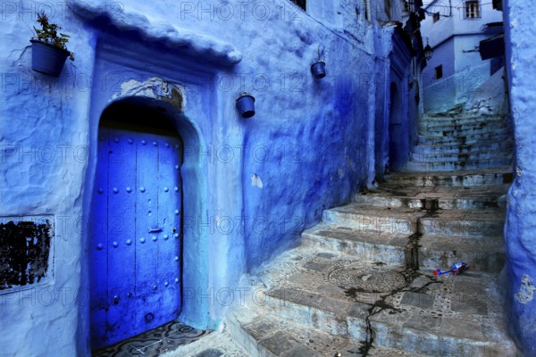 Narrow, blue street with Moroccan-decorated doors and a staircase in Chefchaouen, Chefchaouen, Tanger-Tetouan, Morocco