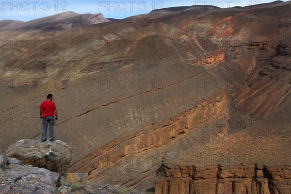 A person wearing a red jacket looks at the Dadès Canyon with impressive rock formations, Dadès Gorge, Morocco