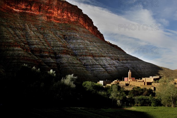 Gorge at sunset with silhouette of a building at the foot of glowing rocks, Dadès, Region, MA