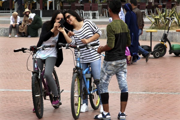 Friends enjoy a bike ride on Agadir promenade, laughing and relaxing, Agadir, Morocco
