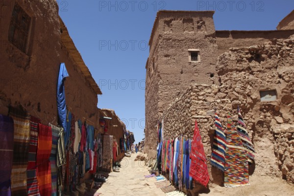 Narrow alley with colorful textile presentation in Ait Benhaddou, Ait Benhaddou, Ouarzazate, Morocco