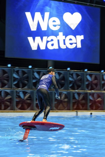 Press photo dynamic photo of eFoil surfer in the large XXL pool in Hall 17 of Messe Boot Düsseldorf, in the background the motto of Messe boot We Love Water, Messe Boot, Düsseldorf, North Rhine-Westphalia, Germany