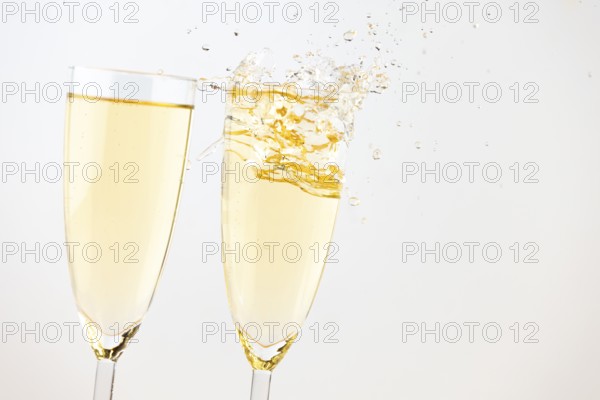 Two champagne glasses with sparkling drink against a bright background
