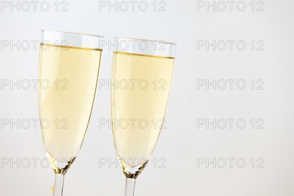 Two champagne glasses against a bright background