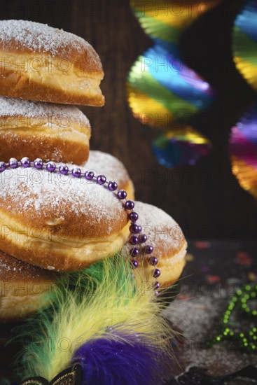 Close-up of Berliners with powdered sugar and pearl necklaces, colorful carnival atmosphere