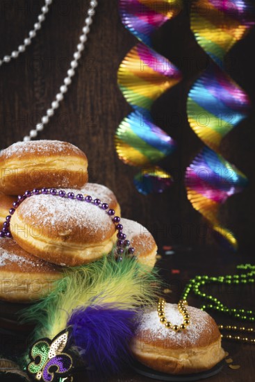 Berliner with powdered sugar, decorated with pearl necklaces and colorful spirals against a dark background, carnival