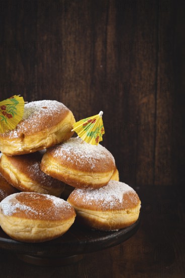 A pile of Berliners with powdered sugar on a dark wooden background, Mardi Gras